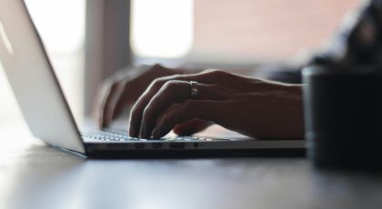 Bir insan laptop bilgisayarında tuşlara basmakta.