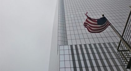 A U.S. flag near a skyscraper.