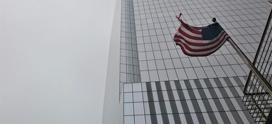 A U.S. flag near a skyscraper.