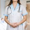 A female doctor is standing upright with her uniform.