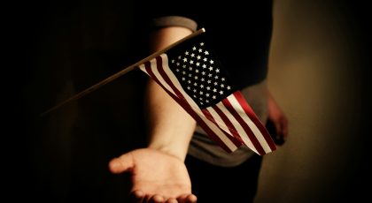 The U.S. flag waves above a person's open palm.