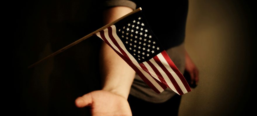 The U.S. flag waves above a person's open palm.