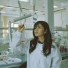A scientist holding a lab tube up in the air, examining it.
