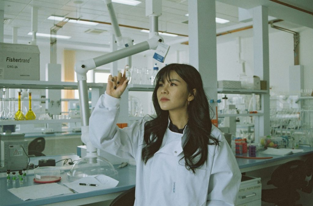A scientist holding a lab tube up in the air, examining it.