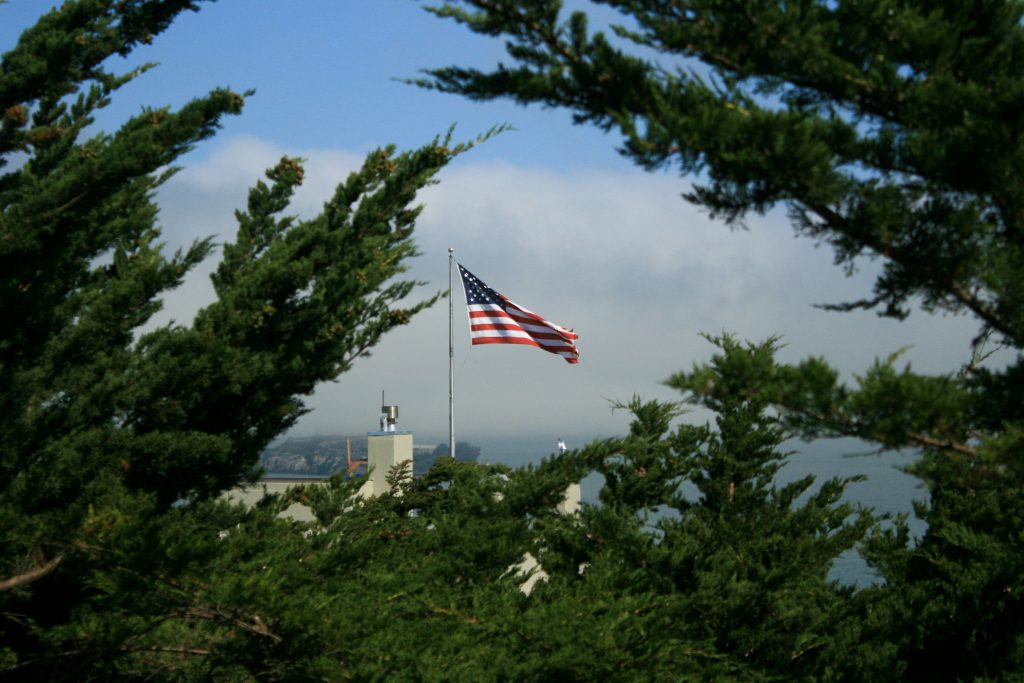 Uzaktan bir yerde Amerika bayrağı, ağaçların arasında dalgalanıyor.