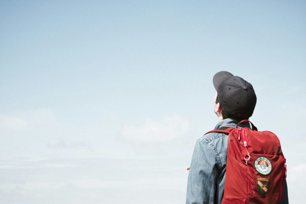 A person with a backpack looking up at the sky.
