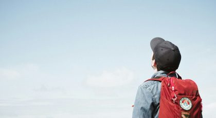 A person with a backpack looking up at the sky.
