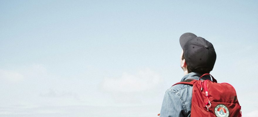 A person with a backpack looking up at the sky.