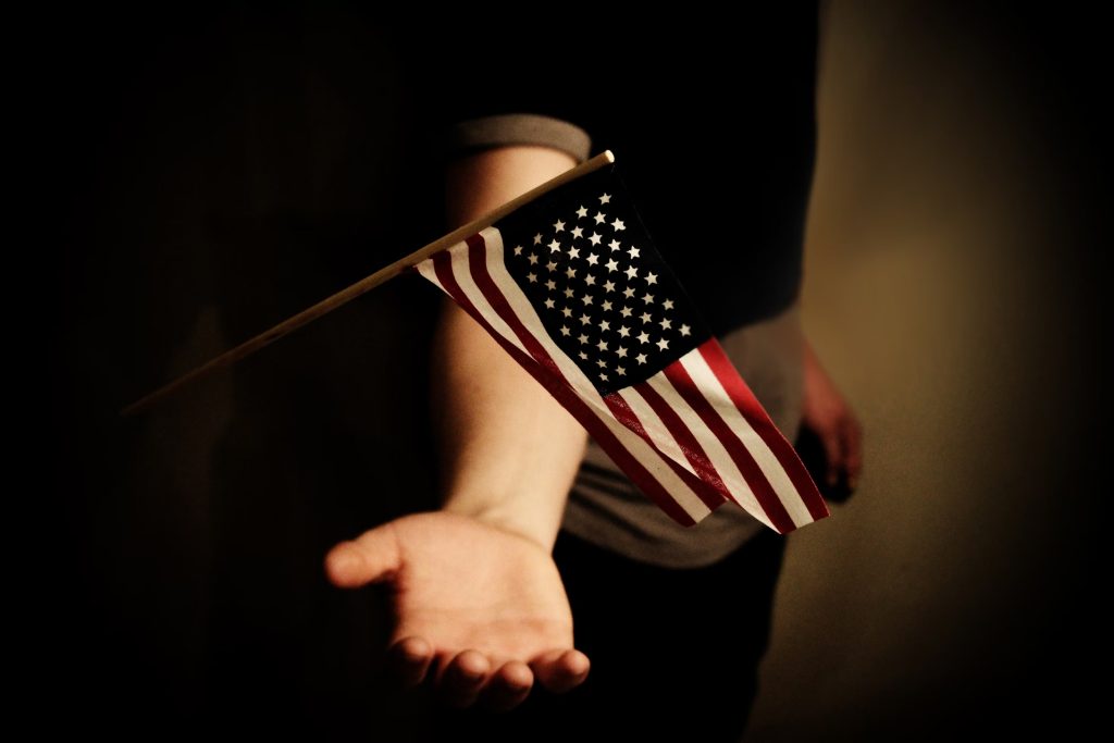 A person with an open palm is about to hold a mini USA flag.
