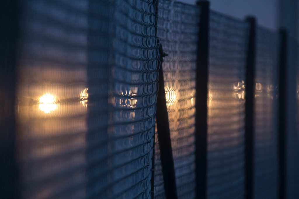 A fence dimly lit at night by a yellow light.