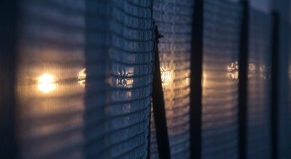 A fence dimly lit at night by a yellow light.