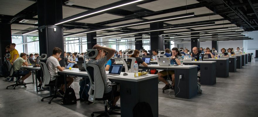 Bir ofis alanında, bilgisayarında çalışan insanlar.